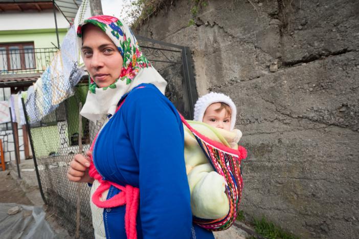 An young mother carries her baby in the traditional way