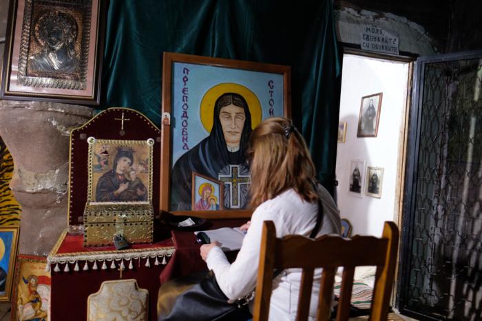 A pilgrim writes her wishes in a special notebook by the cell of Most Blessed Stoyna