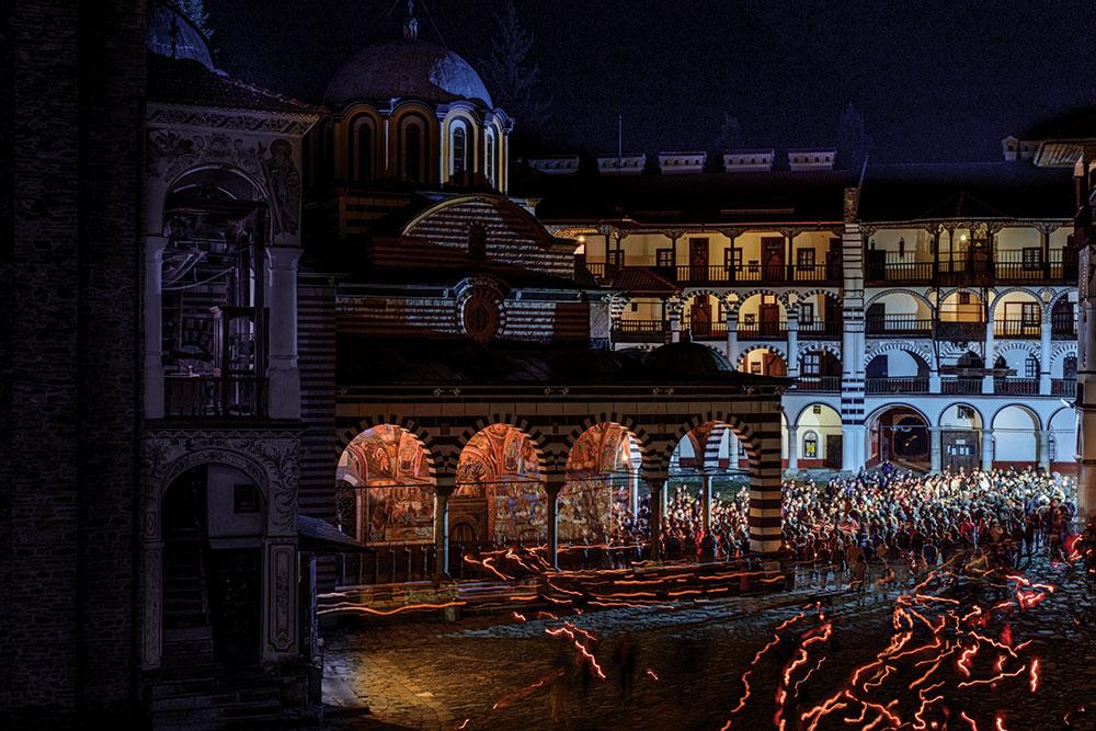 Believers leave Rila Monastery church with lit candles on Easter Sunday